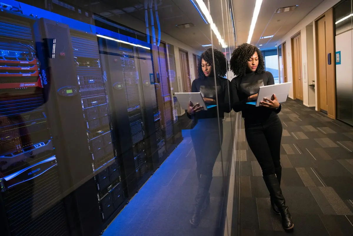 IT professional working on a laptop beside server racks